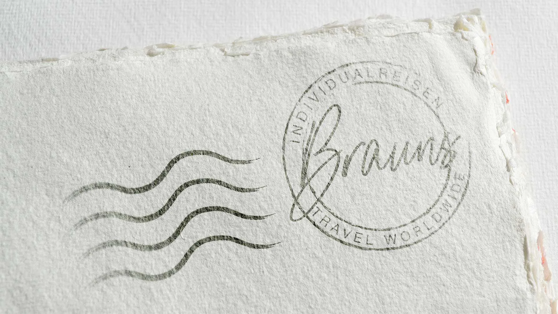 Stempelabdruck von Individualreisen Brauns mit Rundlogo und drei Wellenlinien auf strukturiertem Papier
